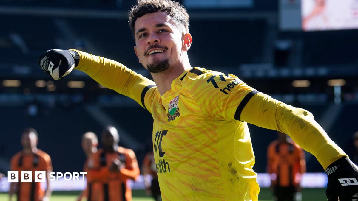 Cieran Slicker celebrates with Barnet fans after a match wearing a yellow goalkeeper jersey