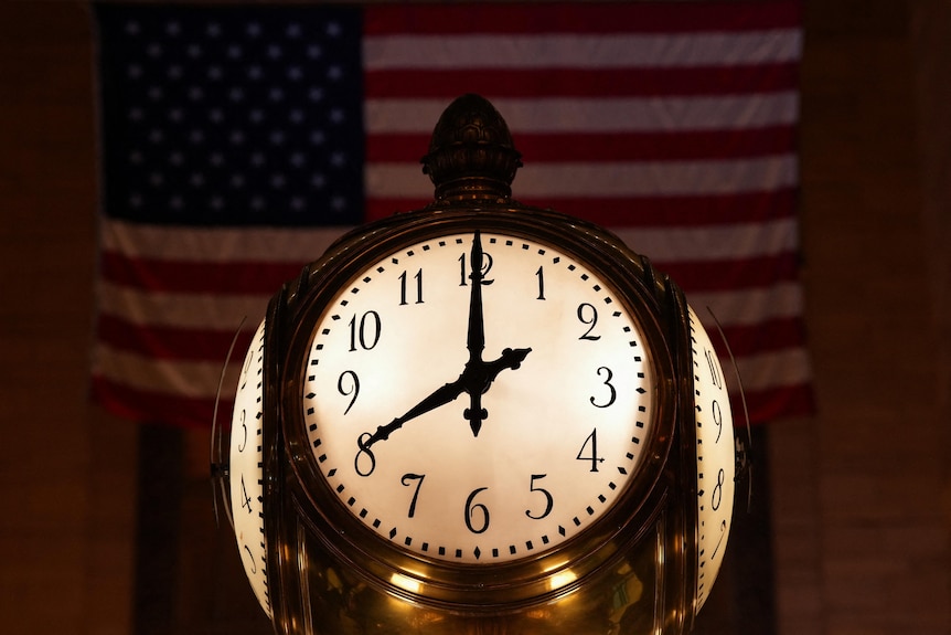 An antique lit-up clock showing a time of 8pm, with a US flag in the background