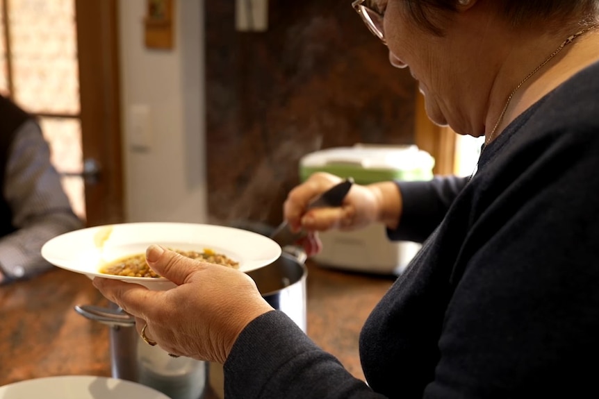 A woman serving lentil soup