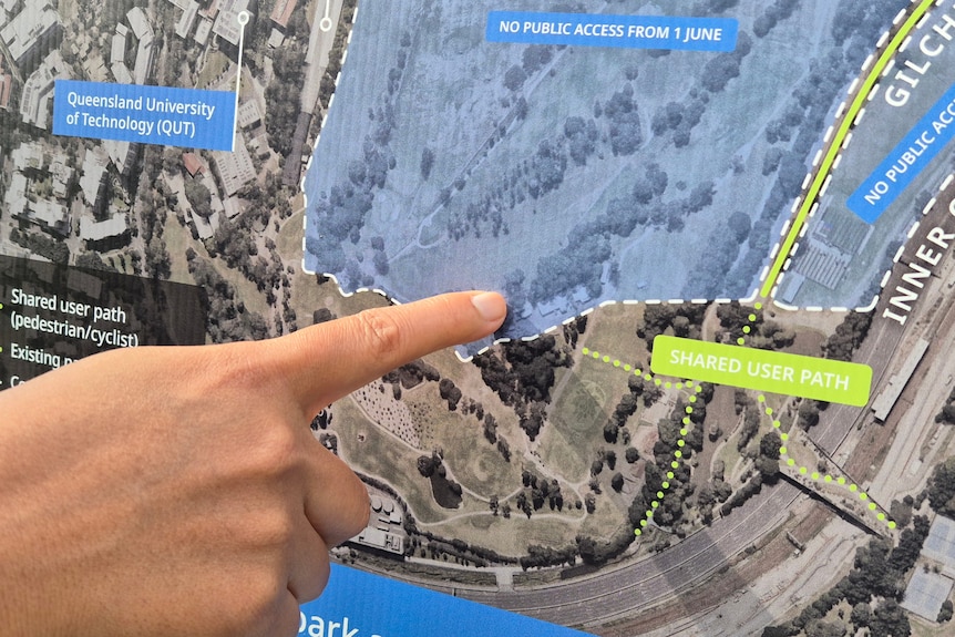 A hand points to a location on a map.