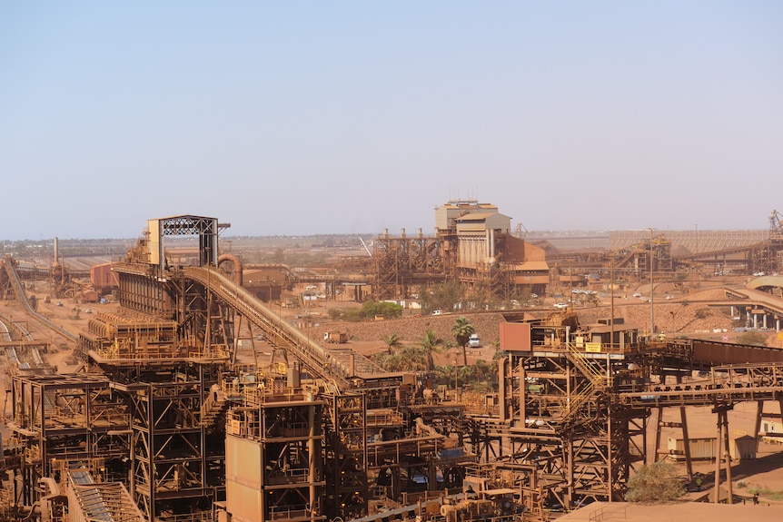 An image of iron ore operations including loaders and conveyer belts