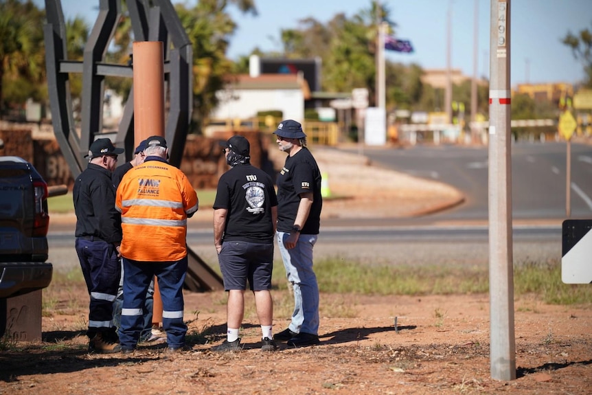 Four workers stand on the side of the road ahead of the strike action.