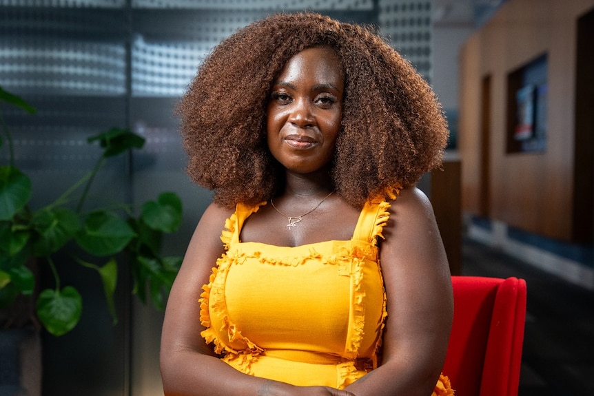 A woman looks at the camera with a neutral expression.