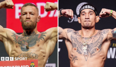 Conor McGregor holds up his arms and Max Holloway holds up his arms