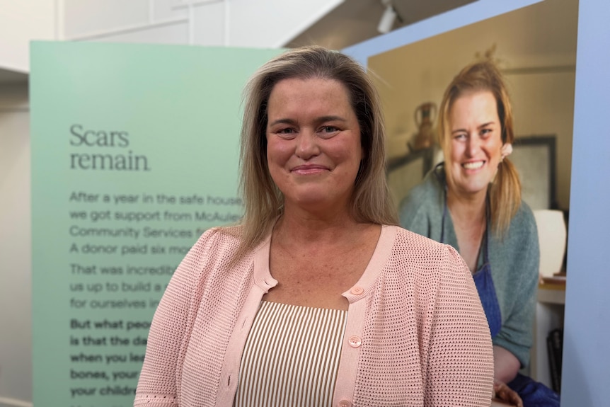 A woman smiles while posing for a photo at a photography exhibition.