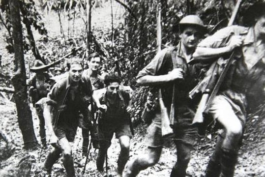 Old photo of soldiers walking along Kokoda Trail