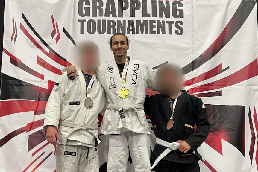 Three men stand on a podium as the top three winners in a Brazilian Jui Jitsu competition.