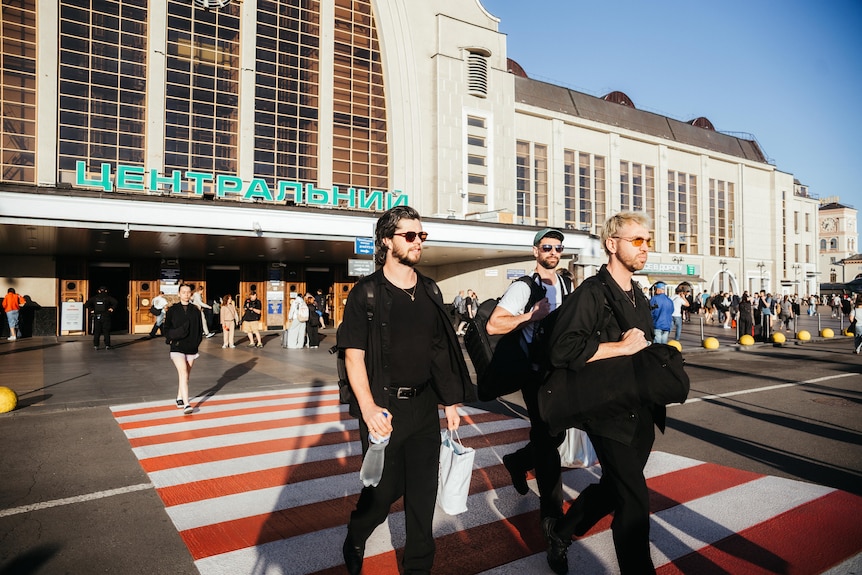 Three men leave a train station.