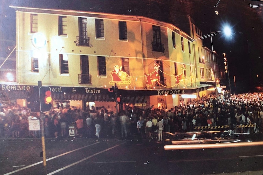 A huge crowd spills out of a a pub.