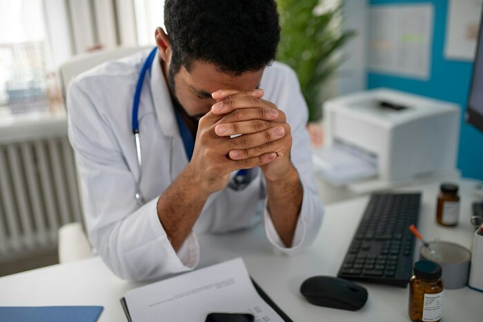 Doctor, ER staff, looking stressed at a desk, dealing with various patients.