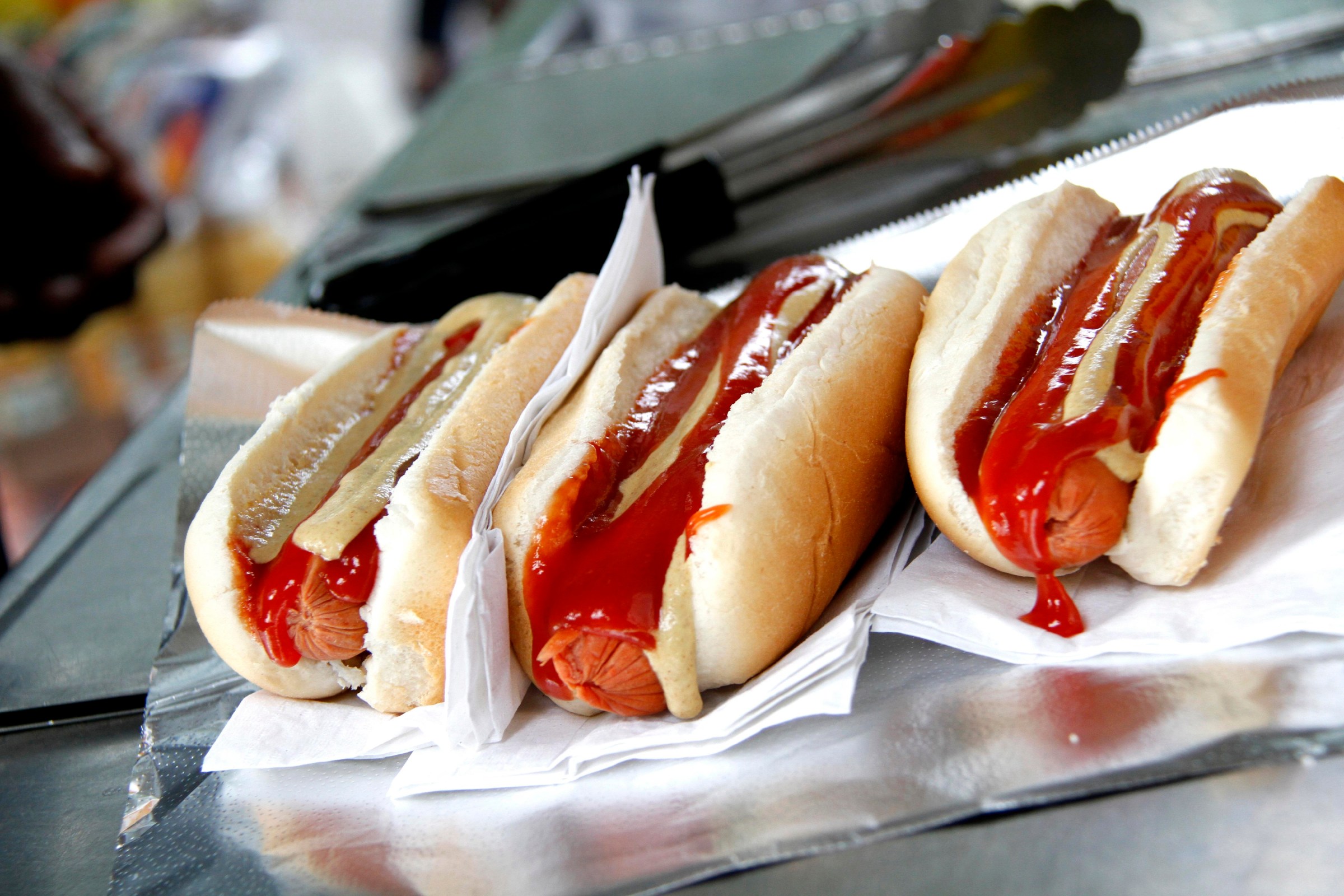 Three hot dogs with ketchup and mustard on buns. (Photo by: Loop Images/Universal Images Group via Getty Images)