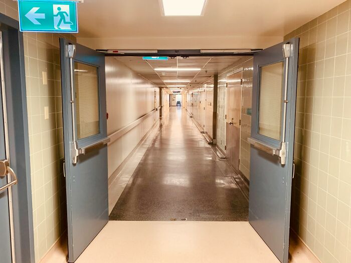An empty hospital hallway with an exit sign, setting the scene for eerie hospital horror stories.