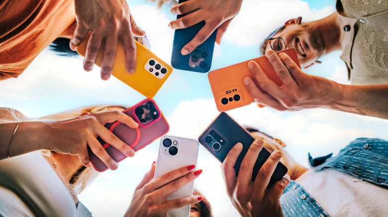 Various iPhone and Android devices held in hand.