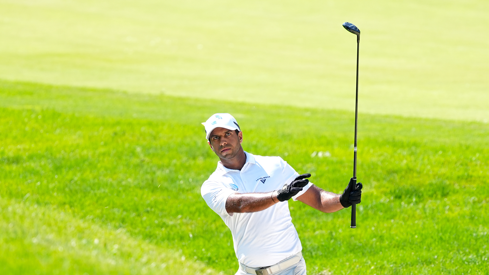 Aaron Rai hits a hybrid from the rough