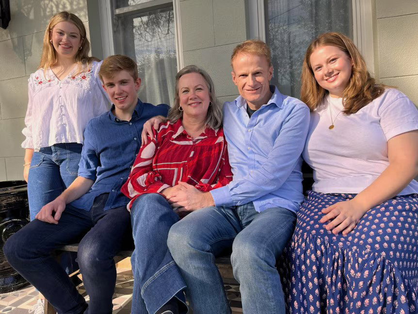 Scolyer with his kids next to him, all smiling on a couch.