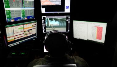 Pictured is a U.S. Air Force photo of an MQ-9A sensor operator with the 11th Attack Squadron inside a ground control station at Creech AFB, Nev. on Nov. 7, 2024.