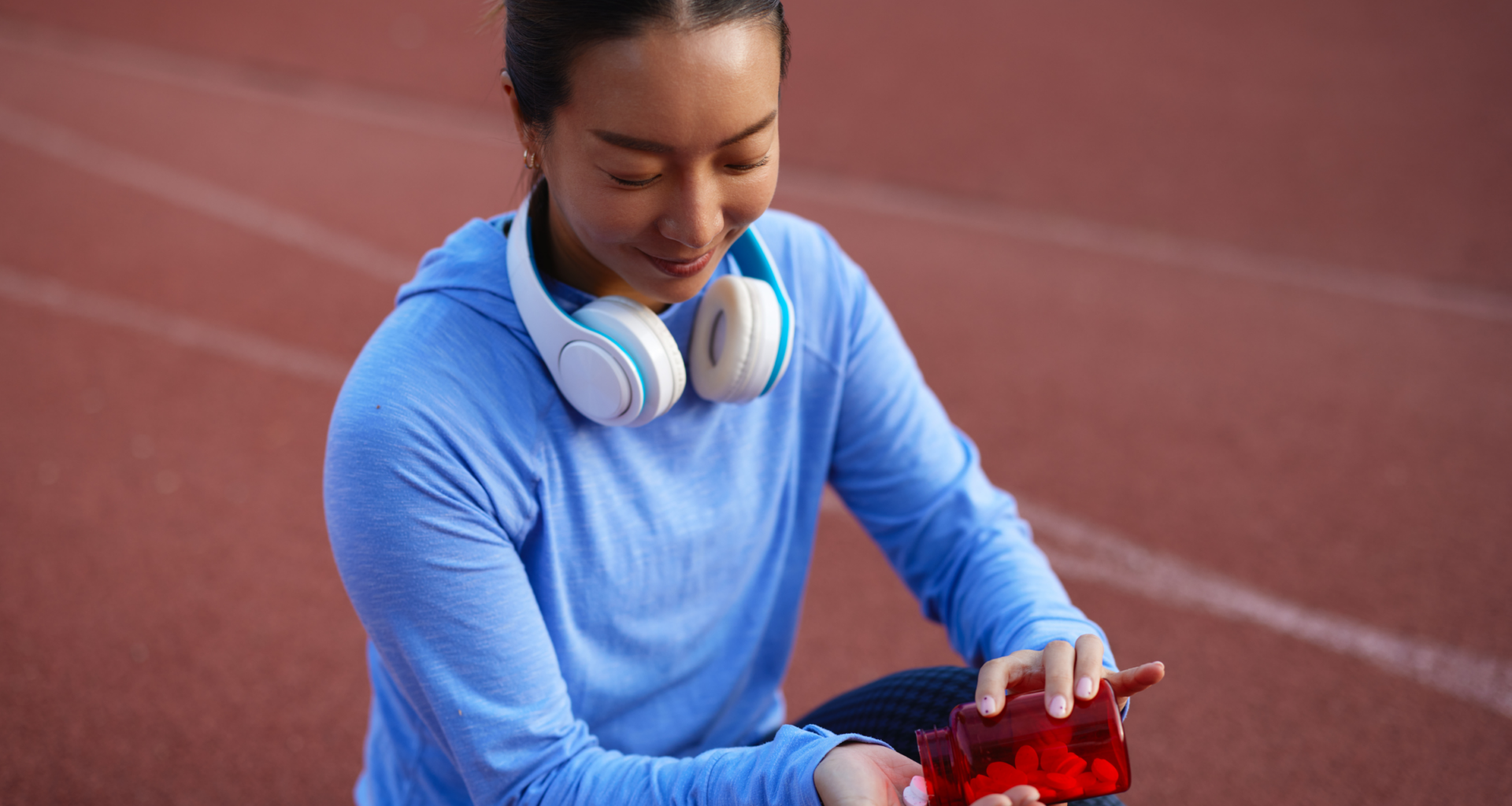 woman sitting on track with supplement pills