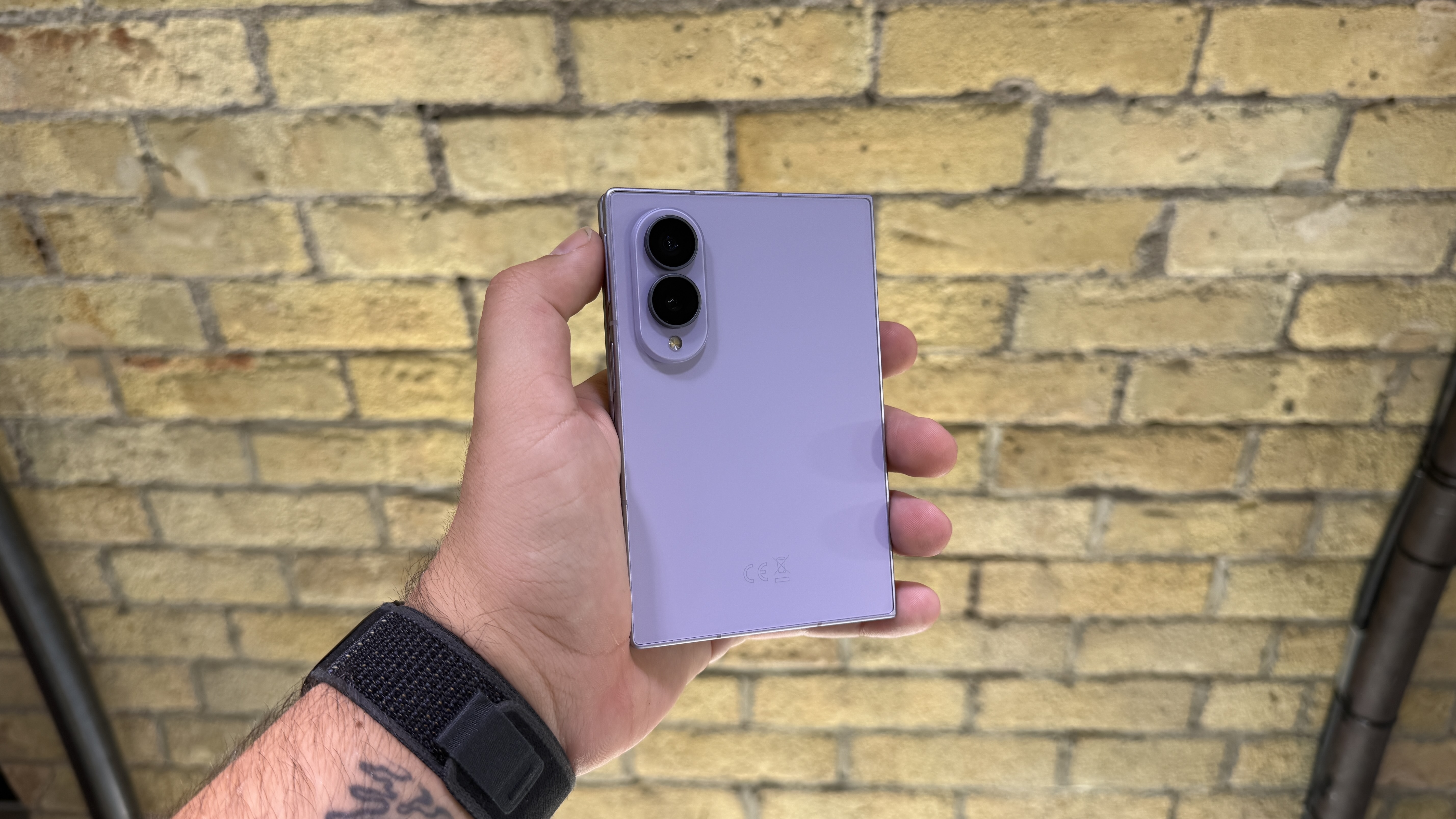 Samsung Galaxy Z Fold 8 and 8 Ultra in hand at a hands-on event, with a brick wall in the background