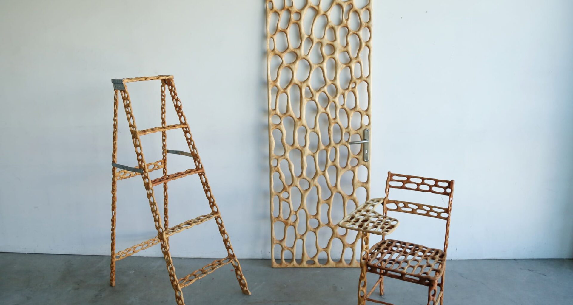 a carved wood ladder, door, and chair with irregularly shaped holes