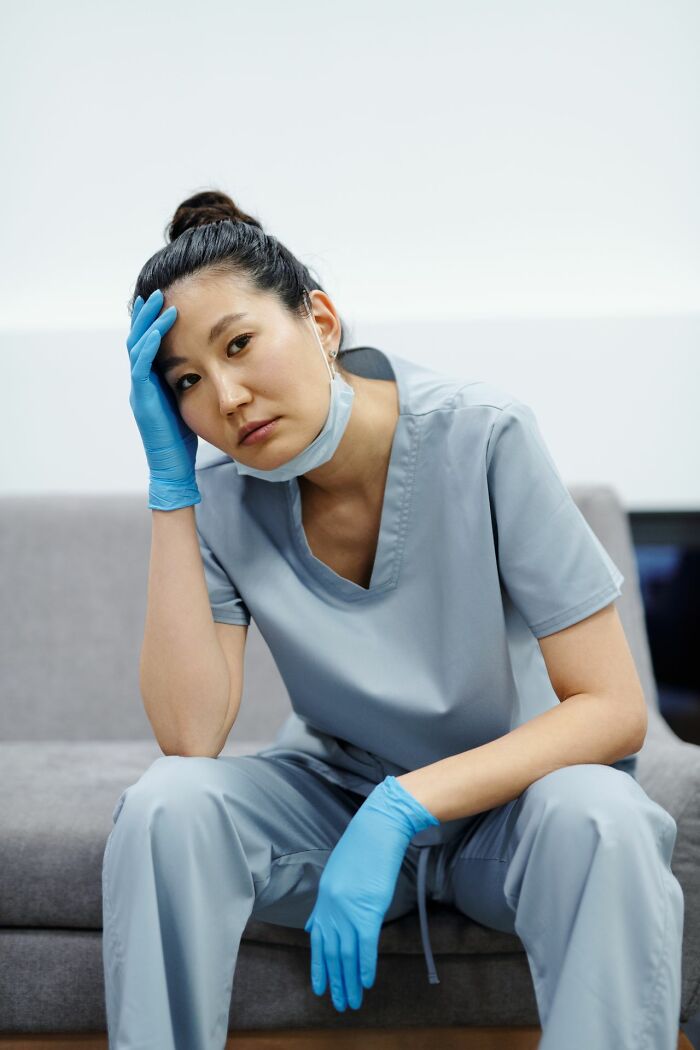 A tired ER staff member in scrubs and gloves, looking exhausted, reflecting the challenges of dealing with patients.
