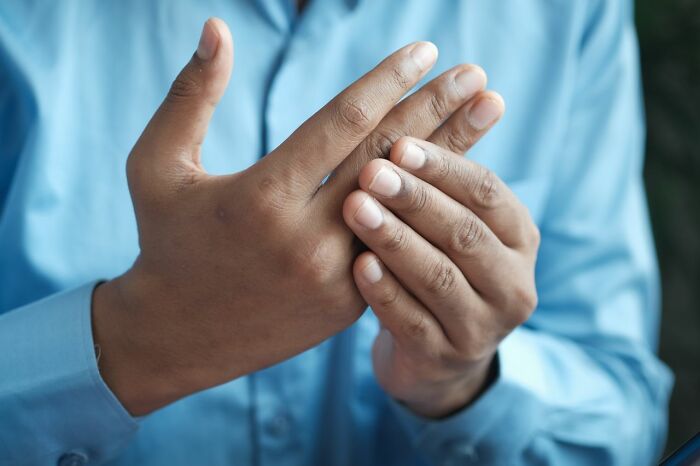 A person rubbing their hand, possibly indicating pain or discomfort, relevant to patients and ER staff.
