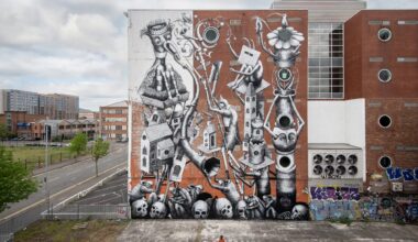 a mural by Phlegm on the side of a building featuring cartoonish figures and objects merged with lots of different shapes