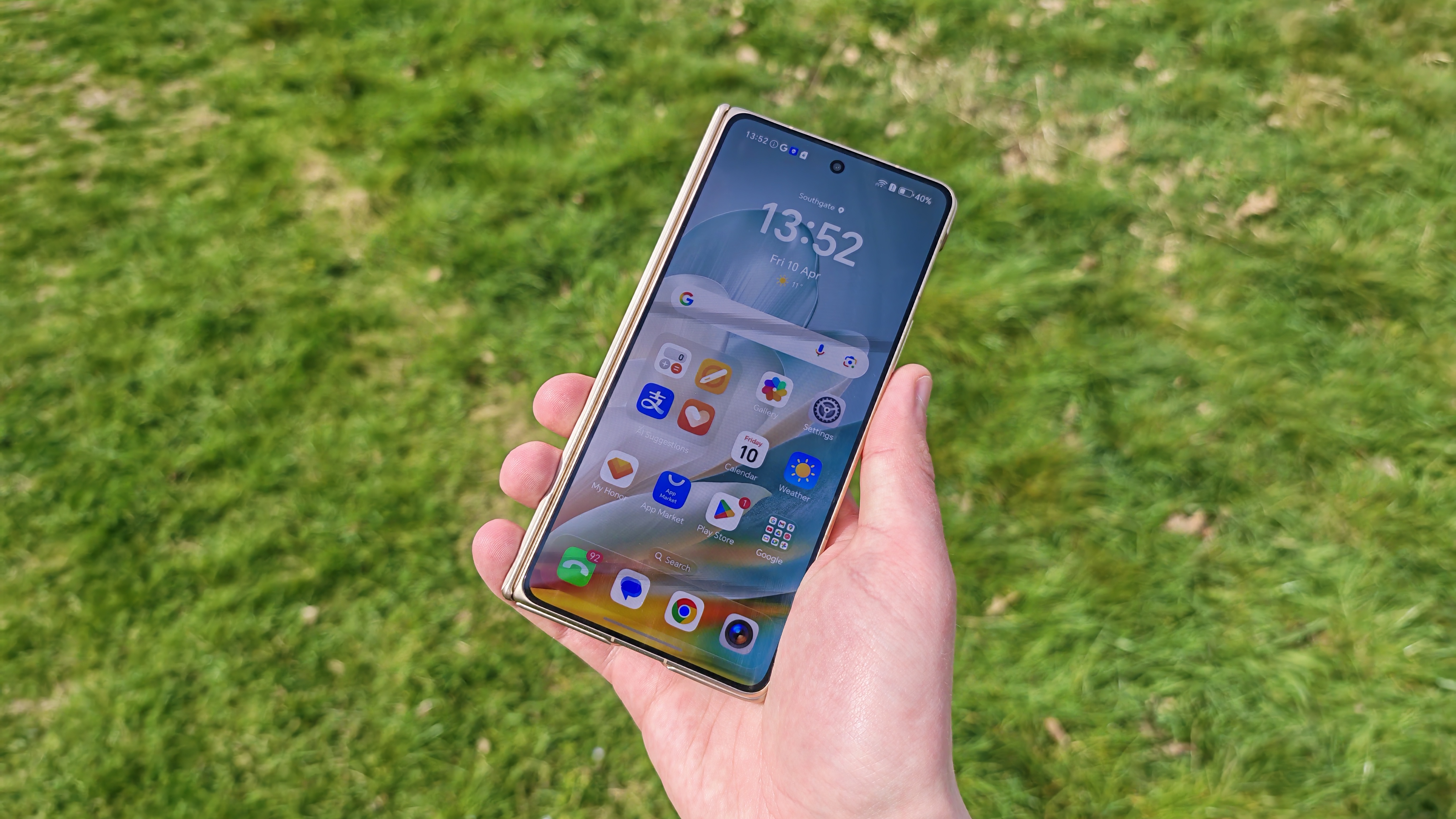 The Honor Magic V6 being held in a sunny field.