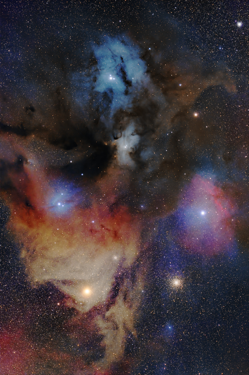 A handful of different types of clouds splatter across the image, with bright stars embedded within. Dust blocks some parts of the clouds. Many small stars cover the background, with a cluster of them sitting in the bottom right beneath all the clouds.