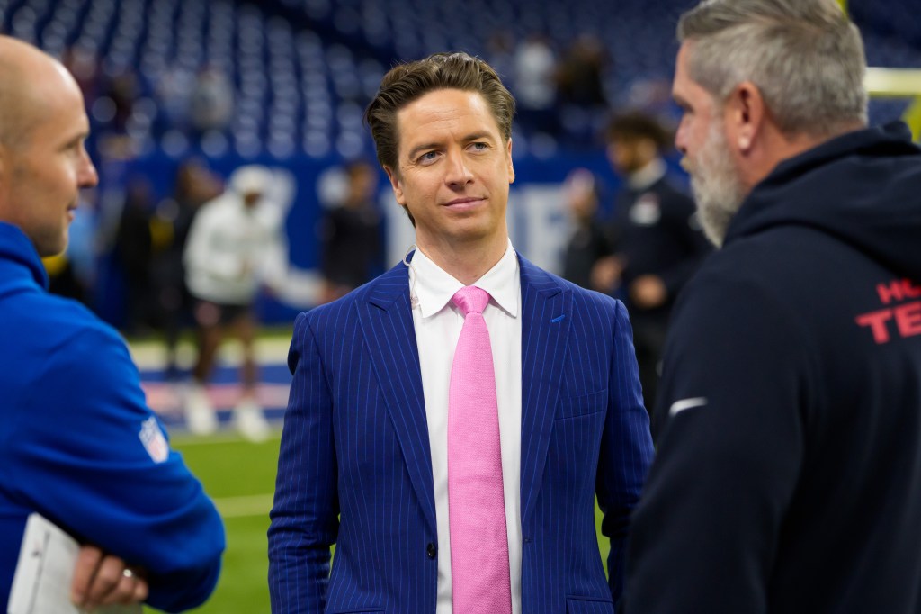 A man in a blue pinstripe suit and pink tie standing on a football field.