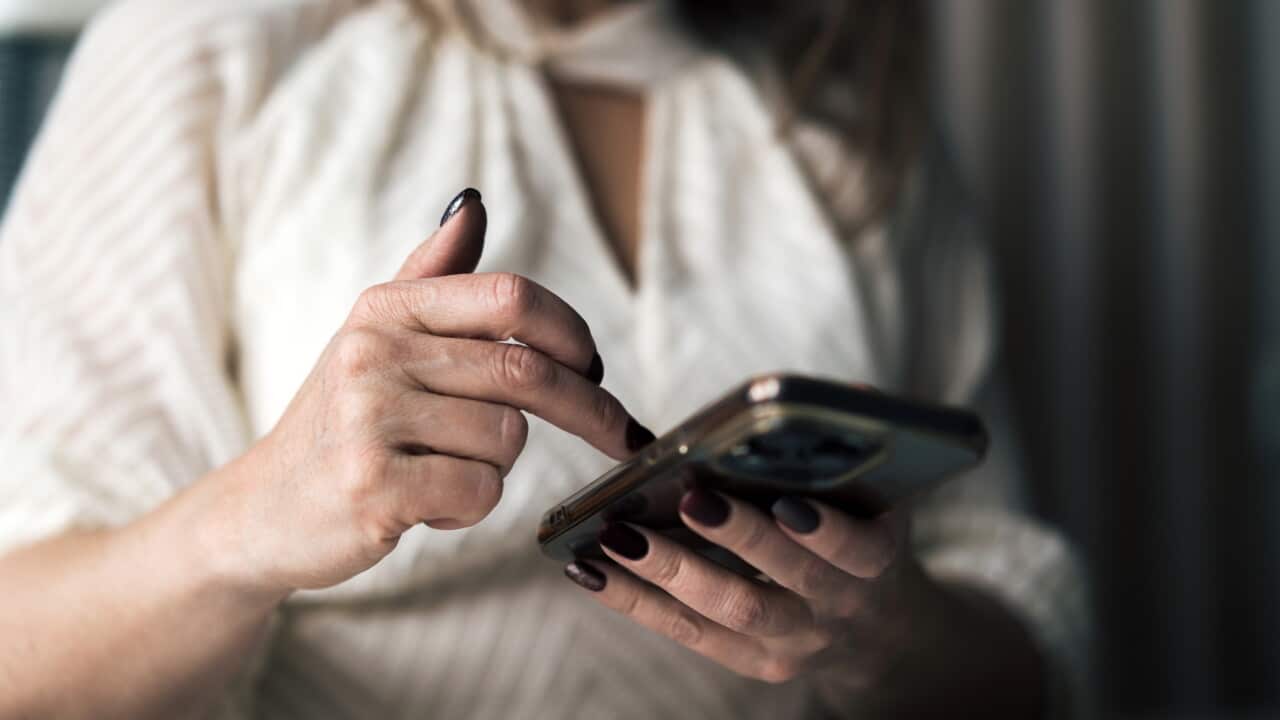 The hands of a woman holding a mobile phone.