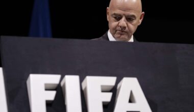 A bald man looks over a podium with large white lettering on it.