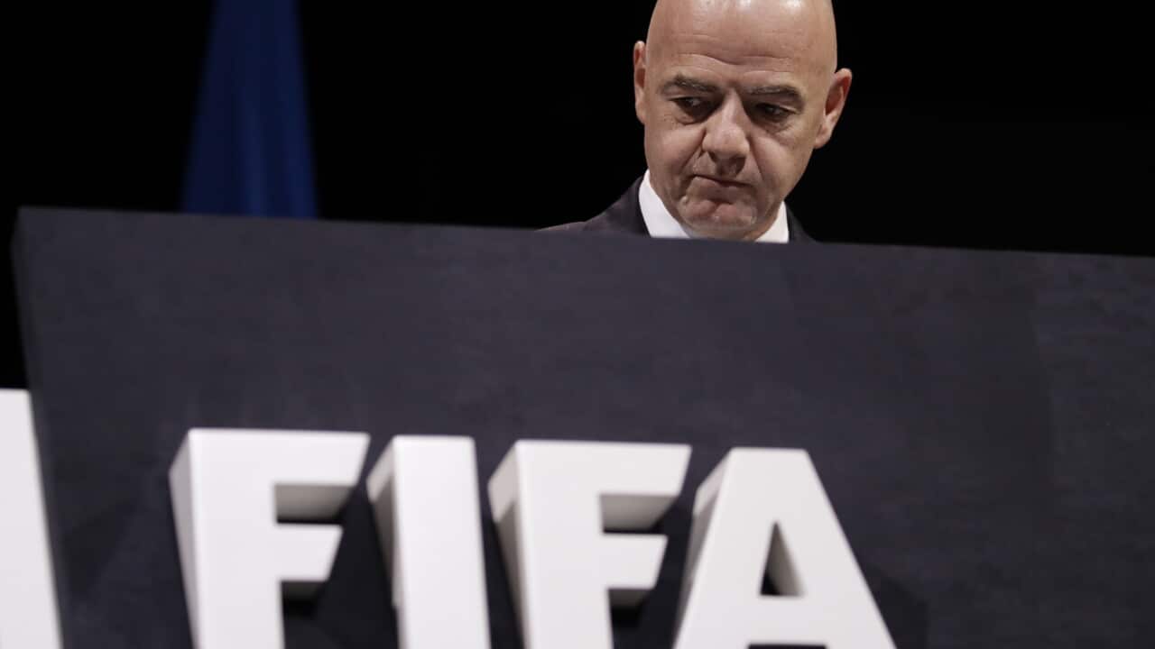 A bald man looks over a podium with large white lettering on it.