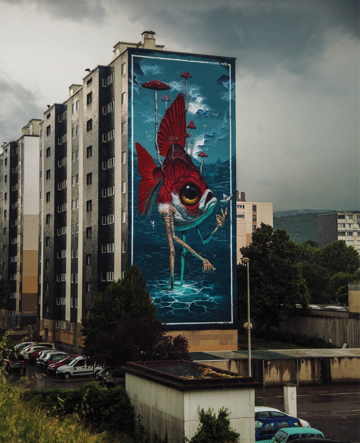 a tall mural on a large apartment building of a fish with long, bird-like legs