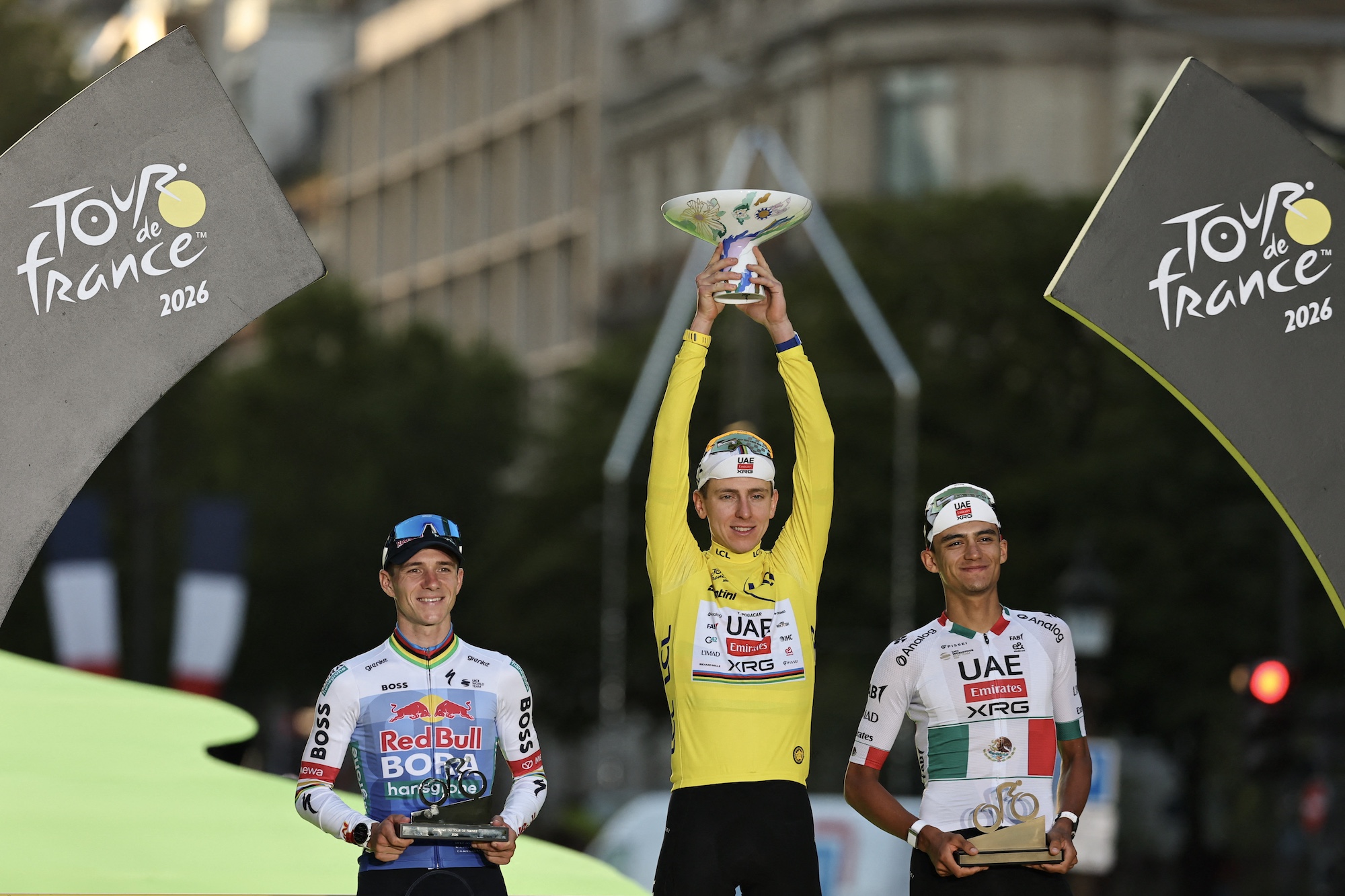 Overall winner UAE Team Emirates - XRG's Slovenian rider Tadej Pogacar celebrates on the on the podium with second-placed Red Bull - BORA - hansgrohe team's Belgian rider Remco Evenepoel and third-placed UAE Team Emirates - XRG's Mexican rider Isaac Del Toro after the 21st stage of the 113th edition of the Tour de France cycling race, 88,7 km starting and finishing in Paris, on July 26, 2026. (Photo by Anne-Christine POUJOULAT / AFP)
