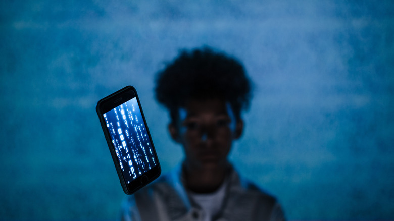 Woman over blue background with a phone showing code running on screen