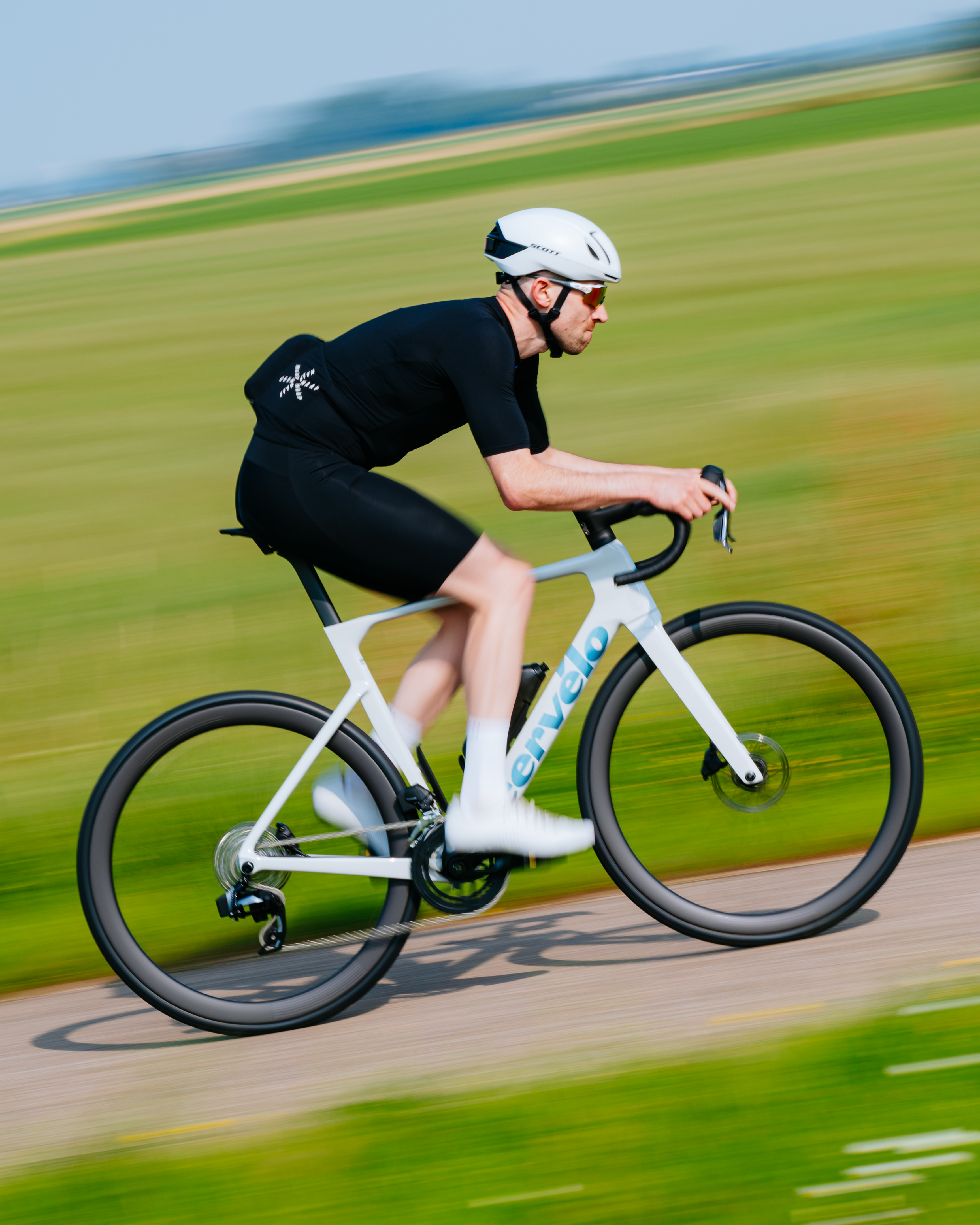 Tom riding a white Cerv&eacute;lo Soloist in front of green fields