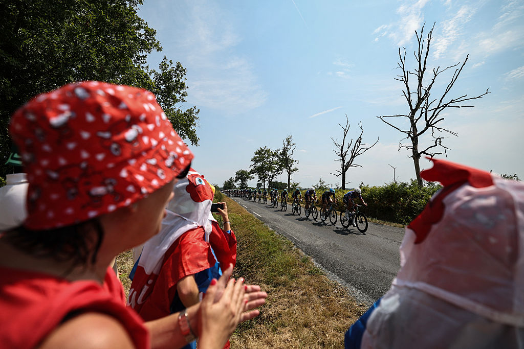 Spectators cheer along the race route as the pack of riders (peloton) cycles during the 7th stage of the 113th edition of the Tour de France cycling race, 175,1 km between Hagetmau and Bordeaux in southwestern France, on July 10, 2026. (Photo by Anne-Christine POUJOULAT / AFP)