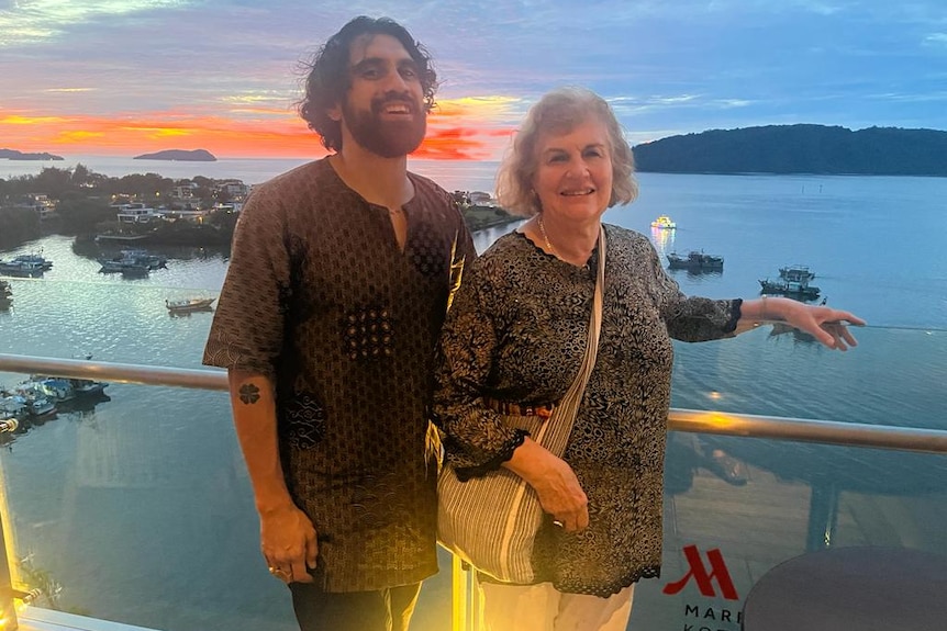 A son and mother smiling in front of a sunset