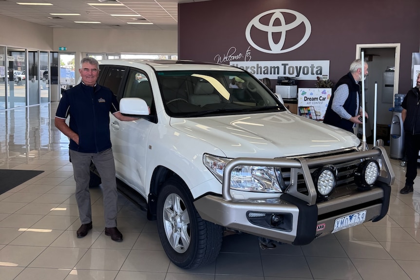 Gary Driscoll stands next to his white LandCruiser in the Horsham Toyota dealership.