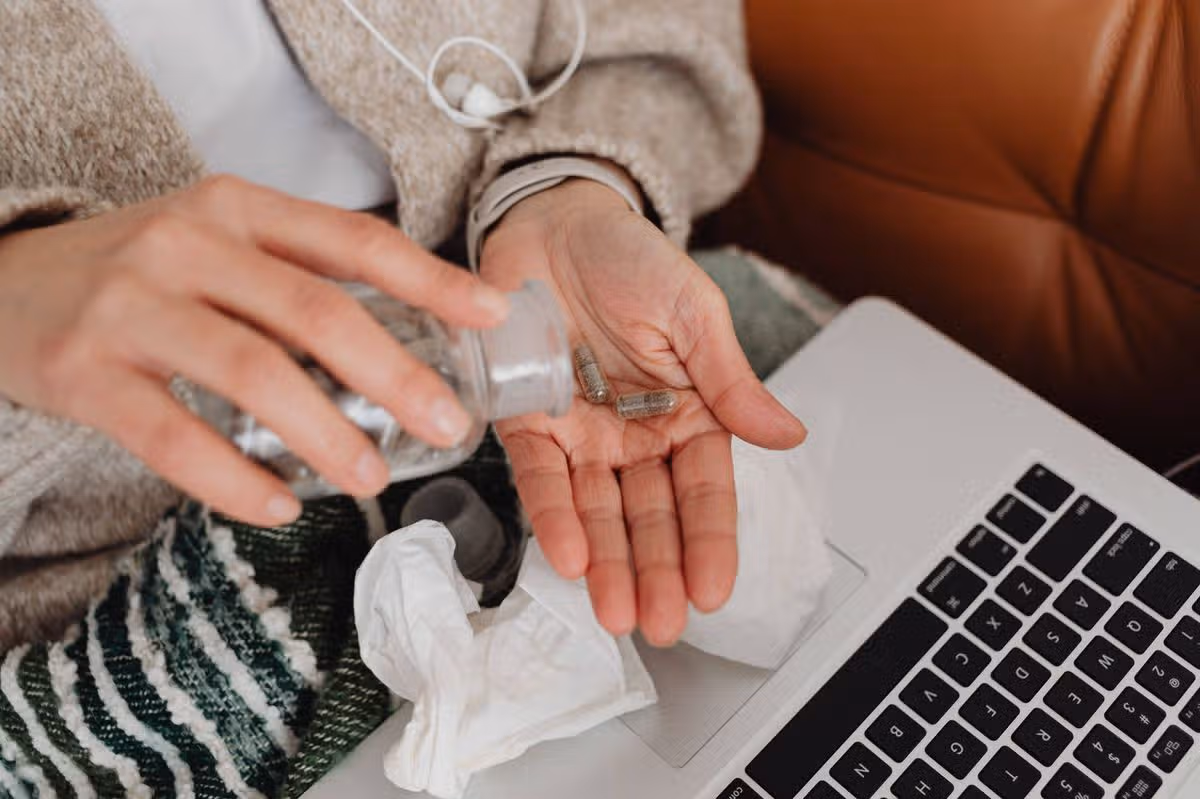 person tipping pills from bottle into palm of hand