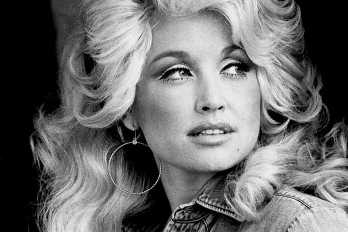 A black and whilte photograph of a woman with blond hair and hoop eartings.