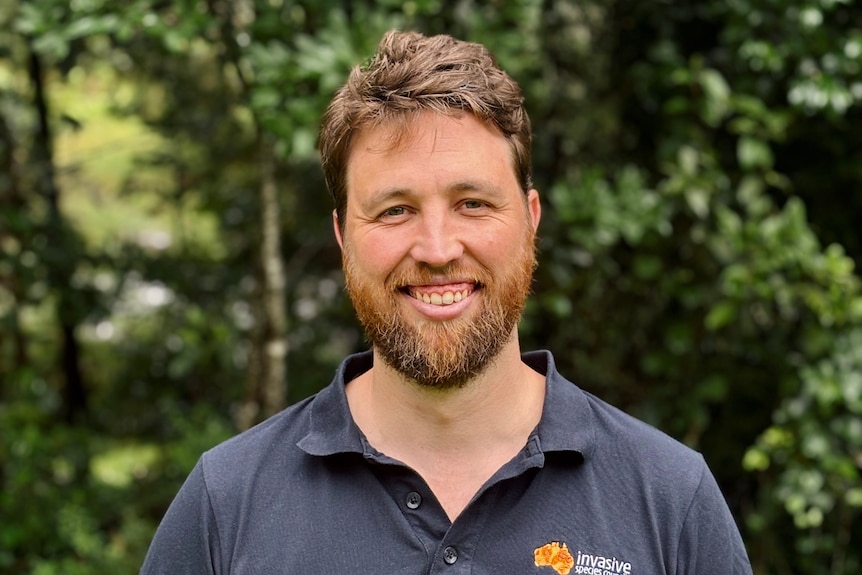 A man in dark grey shirt smiling at the camera.