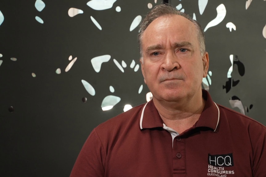 A middle-aged man with short, grey hair wears a branded polo shirt.