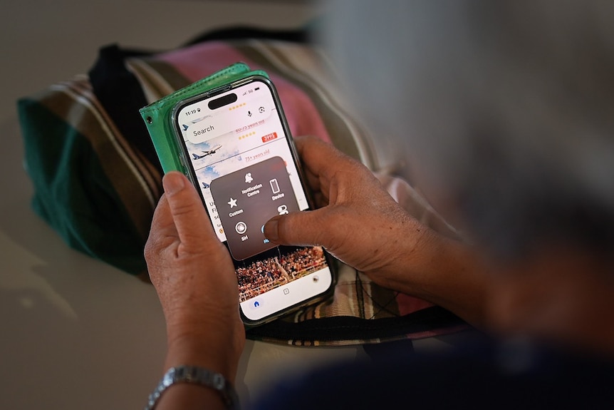 An older woman using a smartphone looking at a travel website