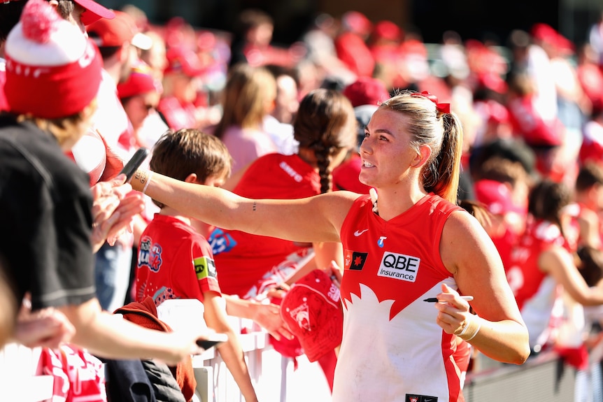 Ally Morphett of the Swans signs autographs.