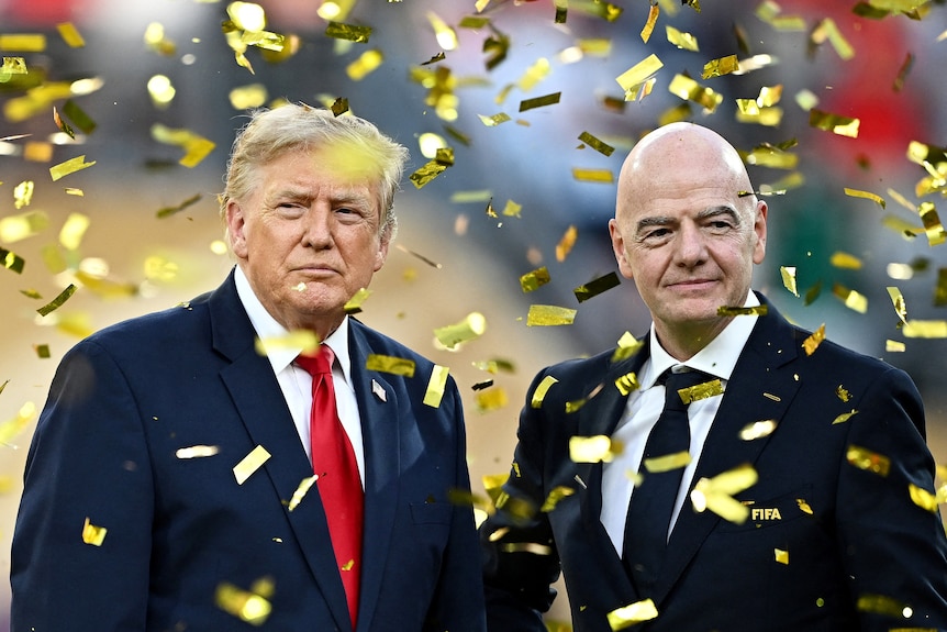 Donald Trump standing next to FIFA President Gianni Infantino. Gold confetti is flying down around them.