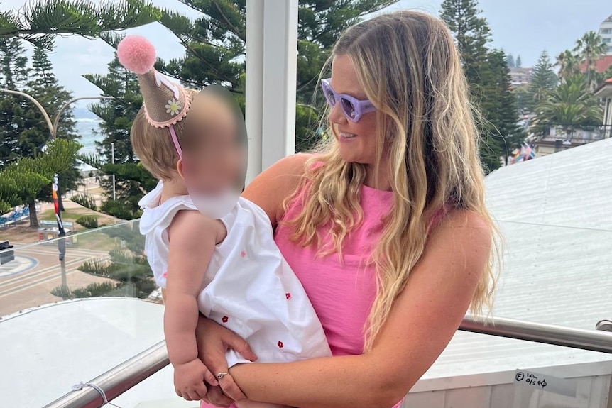 Sydney mother and Coogee local Leah Stewart, who was mauled by a shark, holds a baby.