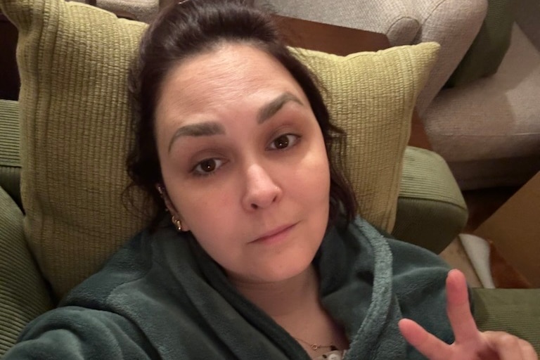 A woman in a robe giving the peace sign.