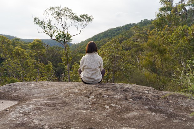 A young woman is enjoying a peaceful view from the top of the top of Joes Mountain, Berowra Valley National Park, NSW, Australia