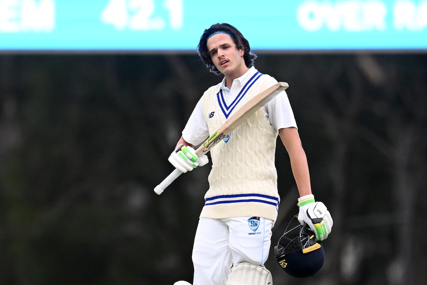 Sam Konstas of New South Wales celebrates his century by raising his bat and removing his helmet